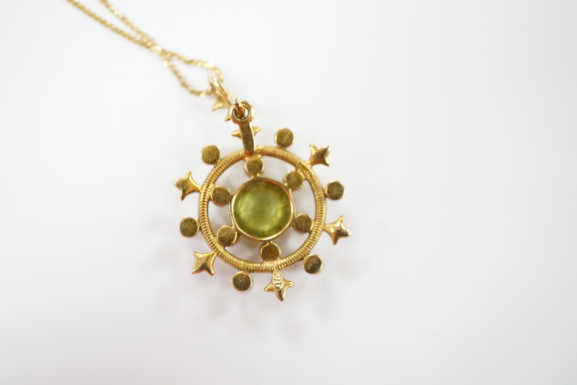 An Edwardian yellow metal, peridot and seed pearl cluster set 'wheel' pendant, overall 30mm, on a later 14k chain, gross weight 5.2 grams.